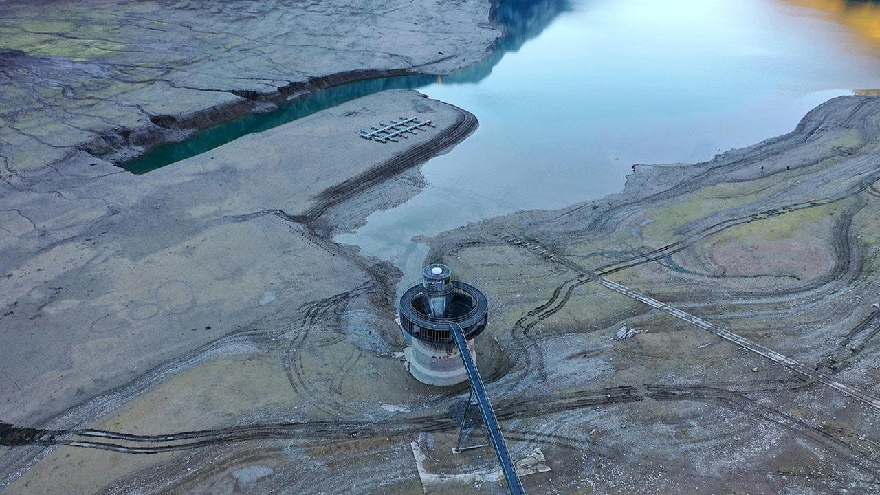 Dry reservoir, with exposed soil and reservoir building