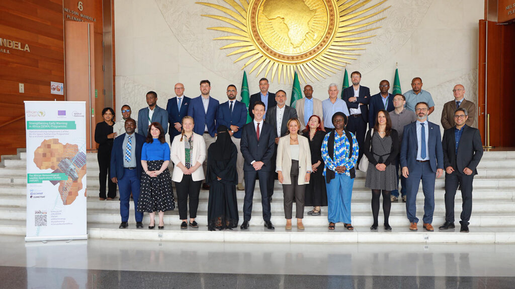 A group of people wearing smart clothes stand on marble steps for a formal photo.