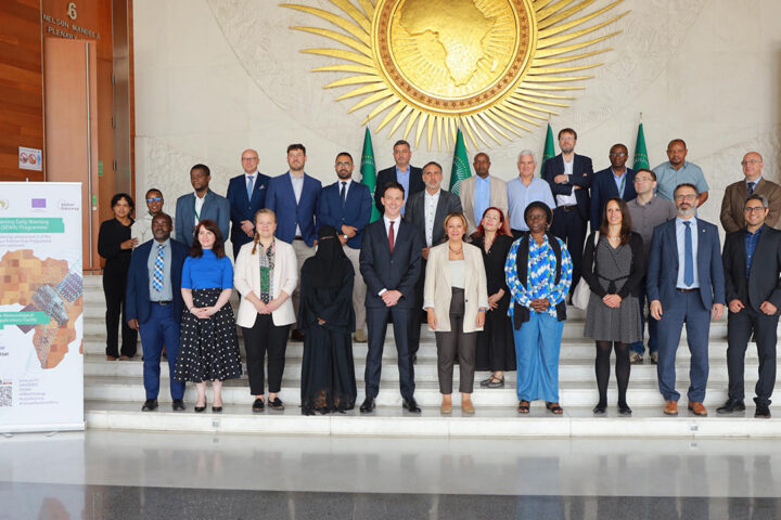 A group of people wearing smart clothes stand on marble steps for a formal photo.