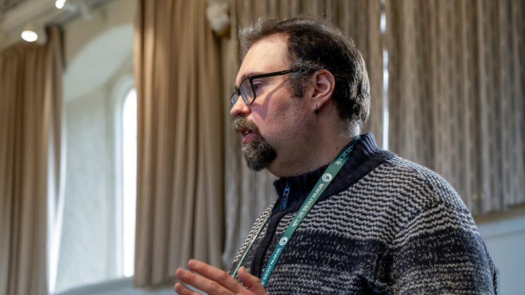A person wearing glasses and a grey jumper.