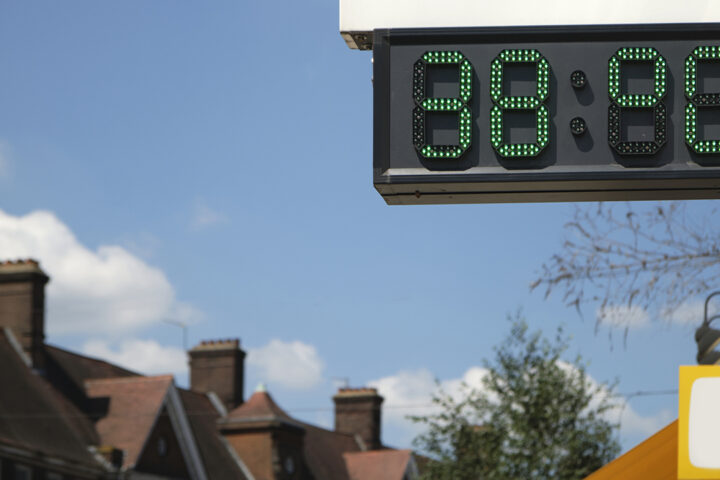 A digital screen shows the temperature reading of 38 degrees celsius. In the background there is a blue sky and rooftops of houses.